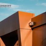 Part of a commercial building with orange and black panels and a surveillance camera.