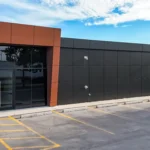 Front of a commercial building with metallic yellow and dark panels.