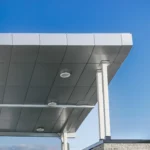 Upward view of a building's roof and canopy with gray ACM panels against a blue sky, showcasing the Gray ACM Commercial Project.