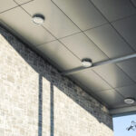 Angled view of a building corner with detailed gray ACM panels and stone veneer.