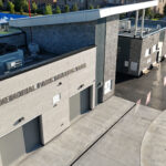 Close aerial shot of the "Memorial Park Skating Trail" sign on a gray brick building with rooftop HVAC units.