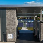 Modern walkway and entrance to a recreational facility, featuring gray ACM cladding and a stone facade.
