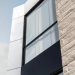 Close-up of a North York home's facade with a black-framed window, ACM panels, and stone cladding.