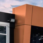 A close-up of the intersection between black and metallic brown ACM panels on a building.