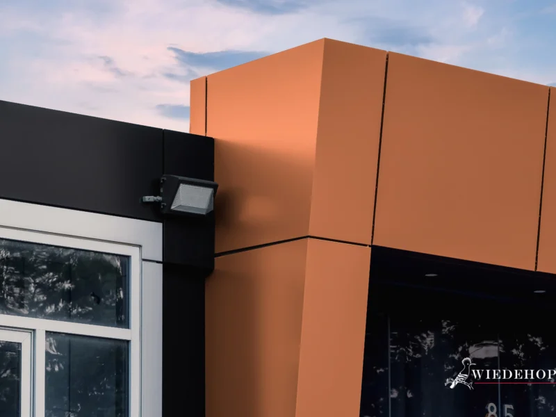 A close-up of the intersection between black and metallic brown ACM panels on a building.