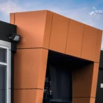 A low-angle close-up of the upper part of a metallic brown and black ACM facade.