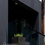 Entrance of a home with Toronto PVC & WPC Shadow Gap siding and glass railing.