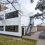 White ACM school building with metal staircase and wooden pergola in North York, Ontario