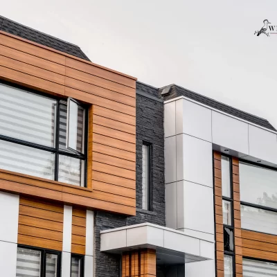 Close-up of the upper facade: wood grain aluminum siding cube next to a white panel section.