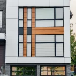Symmetrical vertical shot of a modern wall with wood grain aluminum siding and glass garage doors.