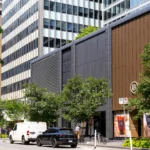 Upper section of a multi-textured commercial facade with gray and brown aluminum panels.