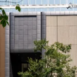 Commercial building facade featuring brown, gray patterned, and cream textured aluminum panels.
