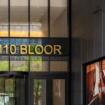 Building entrance with "110 BLOOR" sign and dark gray tile-patterned aluminum panels.