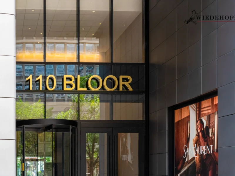 Building entrance with "110 BLOOR" sign and dark gray tile-patterned aluminum panels.