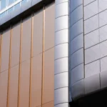 Architectural close-up of bronze and gray aluminum panels on a curved commercial facade.