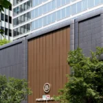 Modern commercial facade with brown, gray patterned, and beige aluminum panels beneath a tower.
