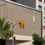 Yves Saint Laurent store front with a cream, vertically textured aluminum panel facade.