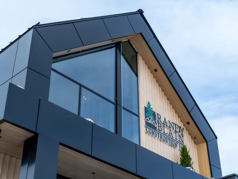 Modern building facade with black Aluminum commercial wall panels and large angled glass windows.