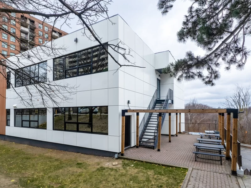 White Siding commercial wall panels on a minimalist building with black-framed windows and an external staircase.