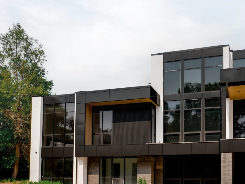 Modern commercial building with black and white WPC commercial wall panels and large, dark-framed windows.
