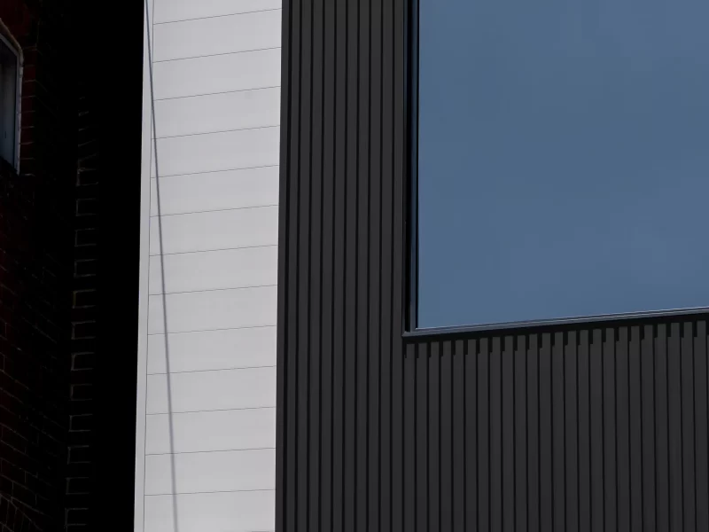Architectural detail showing a corner of a modern house with dark vertical anthracite siding contrasting with white horizontal siding.