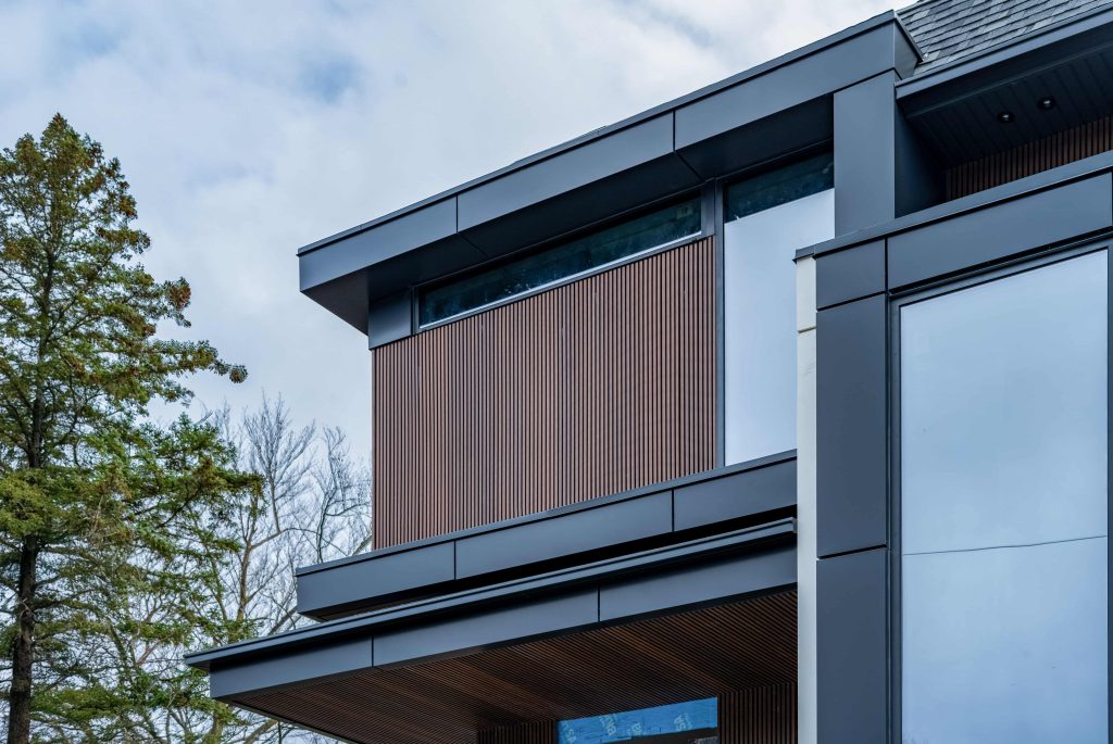 Low-angle view of a modern home featuring brown fluted siding accents and black metal architectural framing.