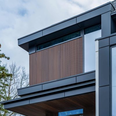 Low-angle view of a modern home featuring brown fluted siding accents and black metal architectural framing.